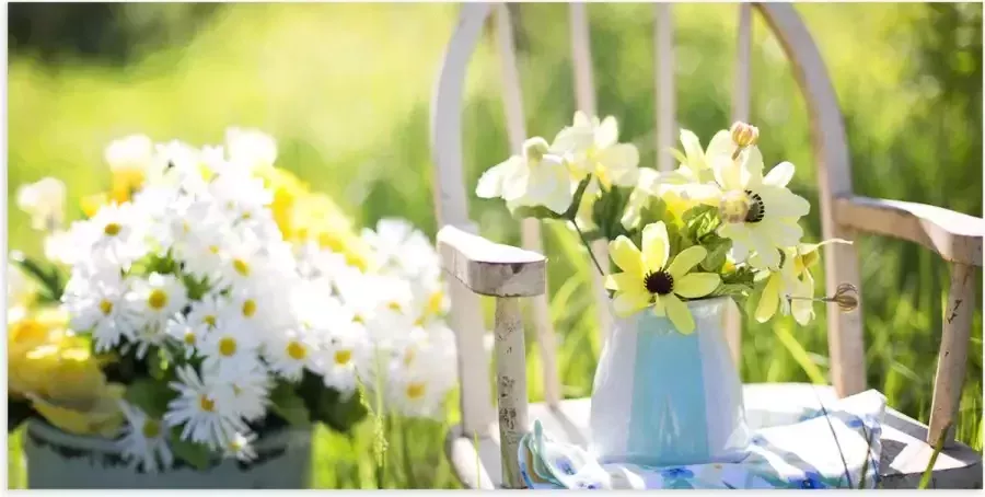 Poster Glanzend – Zakje Bloemen op Witte Traditionele Stoel langs Ton met Bloemen 100x50 cm Foto op Posterpapier met Glanzende Afwerking