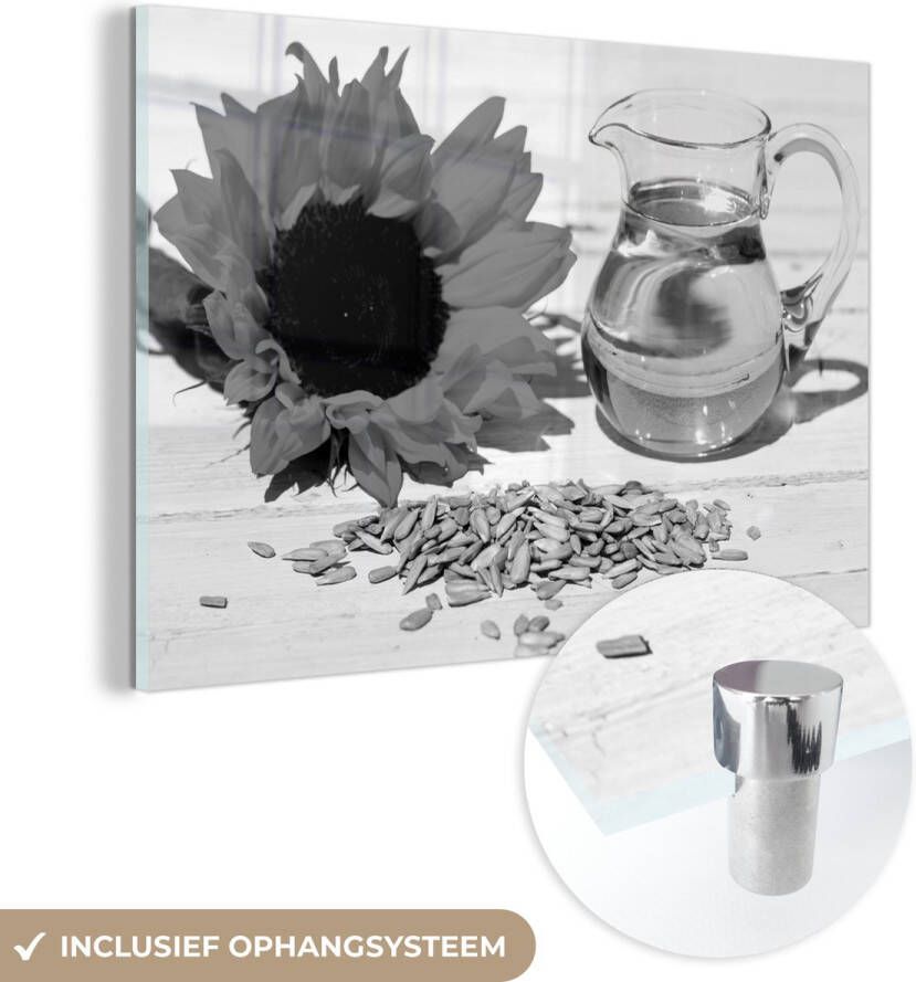 MuchoWow Glasschilderij 180x120 cm Schilderij acrylglas Zonnebloempitten met zonnebloemolie in een klein glas en zonnebloem op witte tafel zwart wit Foto op glas Schilderijen
