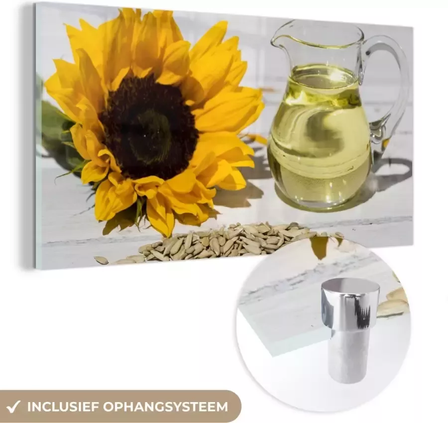 MuchoWow Glasschilderij Zonnebloempitten met zonnebloemolie in een klein glas en zonnebloem op witte tafel zwart wit 180x120 cm Acrylglas Schilderijen Foto op Glas