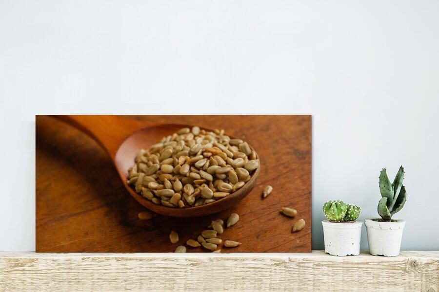 MuchoWow Glasschilderij Houten lepel vol met zonnebloempitten op houten tafel 40x20 cm Acrylglas Schilderijen Foto op Glas