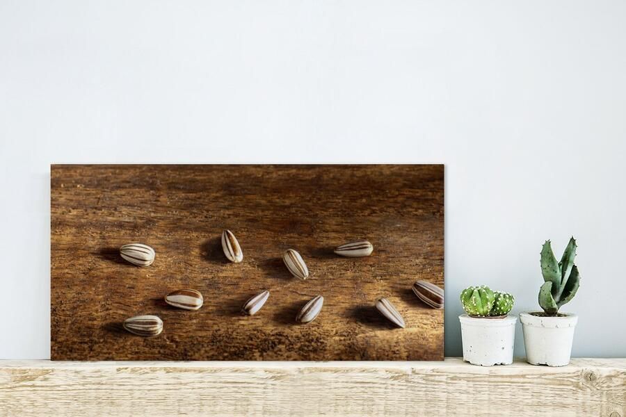 MuchoWow Glasschilderij Tien zonnebloempitten op houten tafel 40x20 cm Acrylglas Schilderijen Foto op Glas