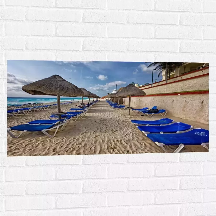 WallClassics Muursticker Blauwe Ligbedden op Strand met Rieten Parasols 100x50 cm Foto op Muursticker