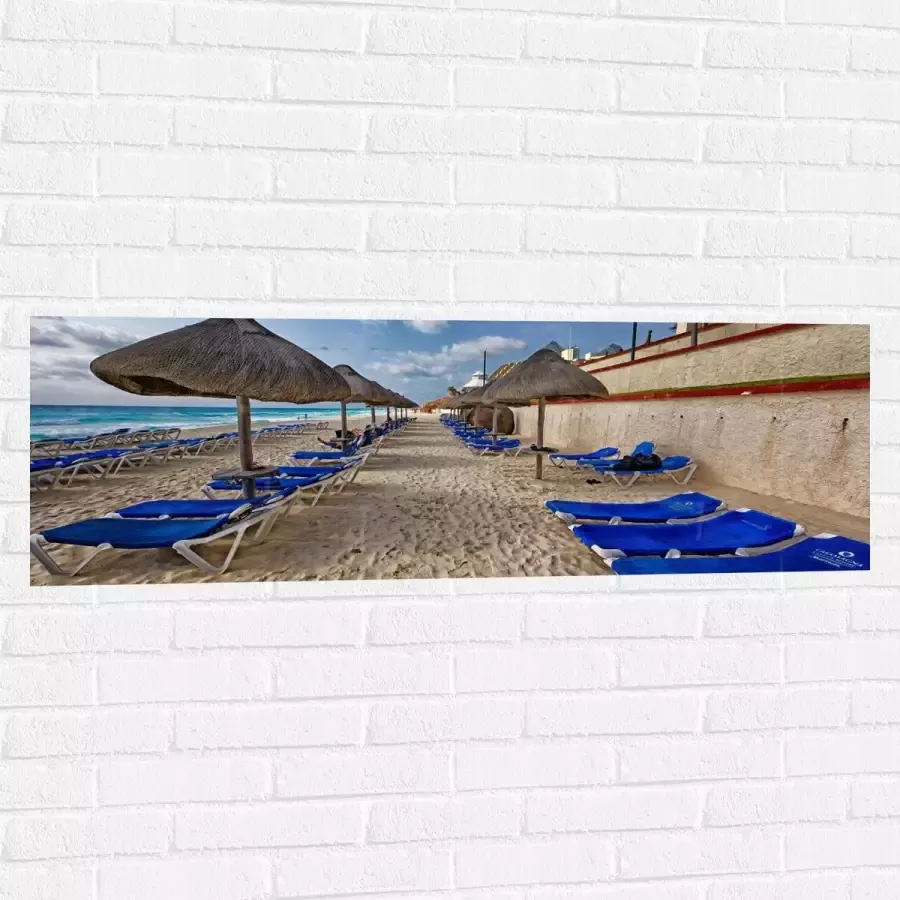 WallClassics Muursticker Blauwe Ligbedden op Strand met Rieten Parasols 120x40 cm Foto op Muursticker