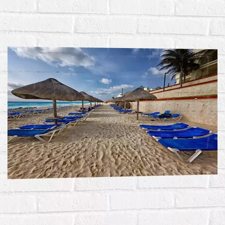 WallClassics Muursticker Blauwe Ligbedden op Strand met Rieten Parasols 75x50 cm Foto op Muursticker