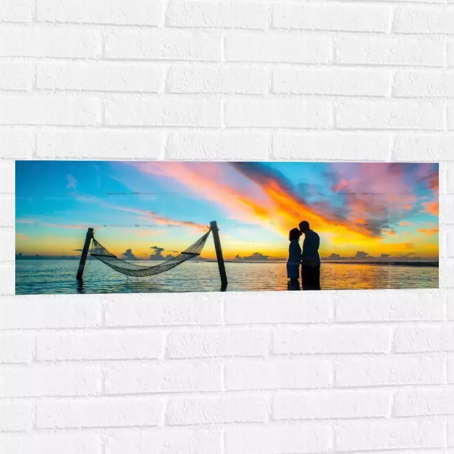 WallClassics Muursticker Verliefd Stel bij Hangmat in de Zee 90x30 cm Foto op Muursticker